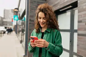 a woman smiling while looking at a phone